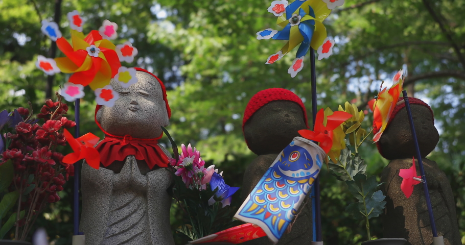 Statue guardian wearing red hat in Tokyo daytime handheld. Minato district Tokyo Japan - 07.25.2019 : It is an old statue at the traditional shrine.