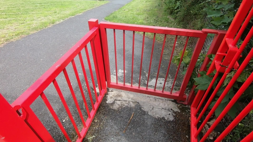 The man enters the playground through the red gate. Slow motion