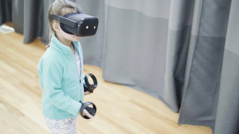 Little girl playing VR kids game in the living room.