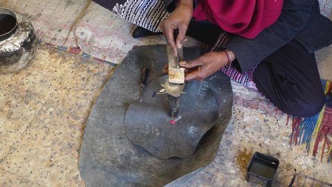 Shot of Tuareg man cutting in wood in traditional way in Algeria
