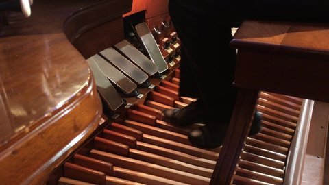 Master organ player using the foot pedals of a pipe organ with amazing skill