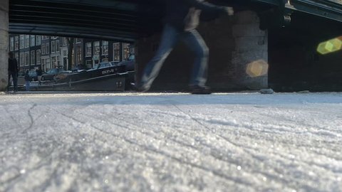 Amsterdam, January 6, 2012. Ice skaters passing underneath a bridge over a canal in Amsterdam. Low angle shot.