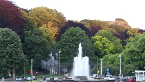 Brussels, Belgium - May 2019: Fountain on the background of colorful trees in a park near the Atomium, an iconic building in Brussels.