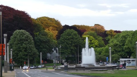 Brussels, Belgium - May 2019: Fountain on the background of colorful trees in a park near the Atomium, an iconic building in Brussels.