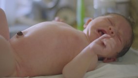 Slow motion shot of a newborn baby crying while mother is giving her a bath with a towel
