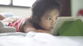 Asian child cute or kid girl watching tablet or smartphone for video clip or cartoon 