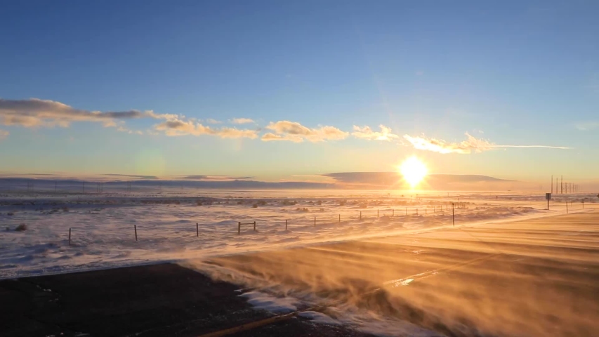 Beautiful sunset in winter with snow being blown over road. Wyoming USA. Static