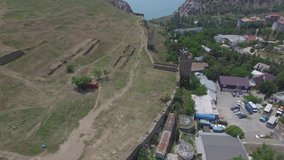 Aerial 4k video of of the Genoese fortress in resort town Sudak on the sea coast, Crimea. View of castle wall and towers.
