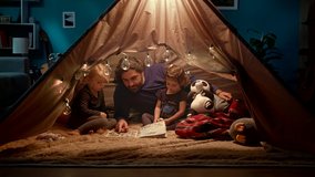 Dad with his daughters reading a book in a handmade wigwam in the living room - Powered by Shutterstock - Get 15% off with code: PIKWIZARD15