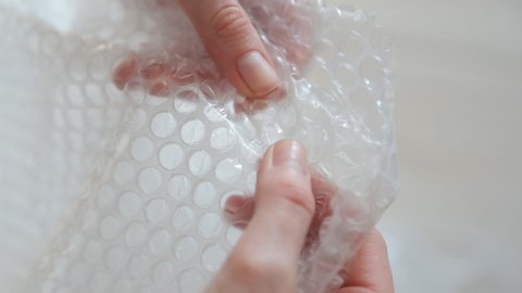 A woman presses a bubble wrap