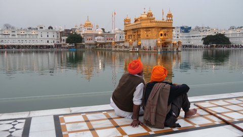 two sikh men sitting beside golden temple' s pool in amritsar, india- 4K 60p