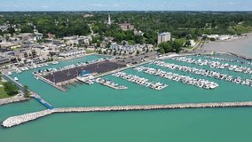 Beautiful aerial video of the marina area of Port Washington Wisconsin. Featuring the iconic art deco lighthouse, blue waters, boats, downtown buildings, Saint Mary's Church