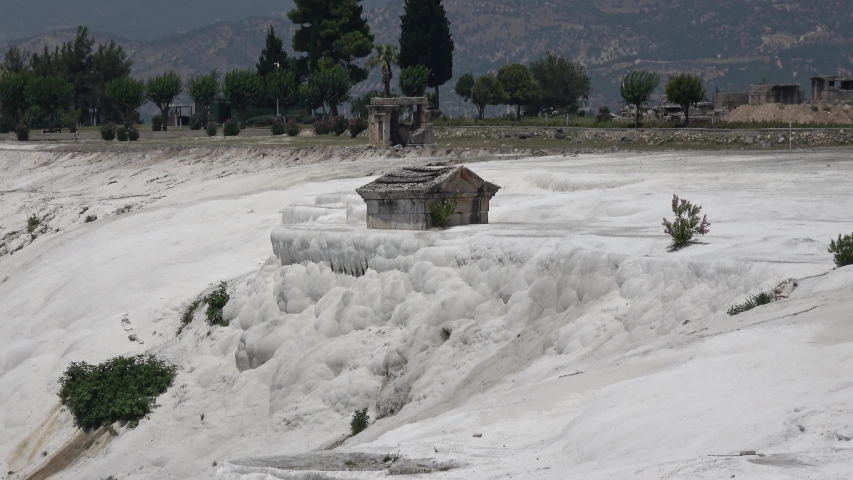 Pamukkale, Denizli, Turkey - 16th of July 2019: 4K Zoom out cotton terrace with tombs in Pamukkale above the valley
