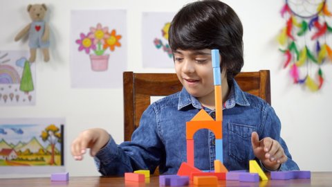 Young Indian boy playing with wooden building blocks and making a house. Cute little boy playing with toys at home -Learning and developing motor skills