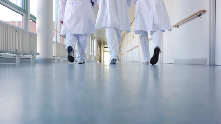 Three doctors walking down a corridor in hospital seen from behind Royalty-Free Stock Footage #1034989475