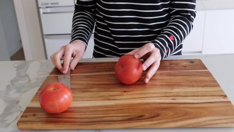 Woman cutting a tomato in slow motion