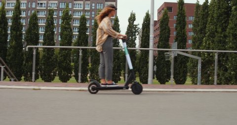 girl rides an electric scooter or e-scooter roller in hamburg city germany, ecological e mobility in the urban city, 4k Steady Parallel Side Shot, modern transportation