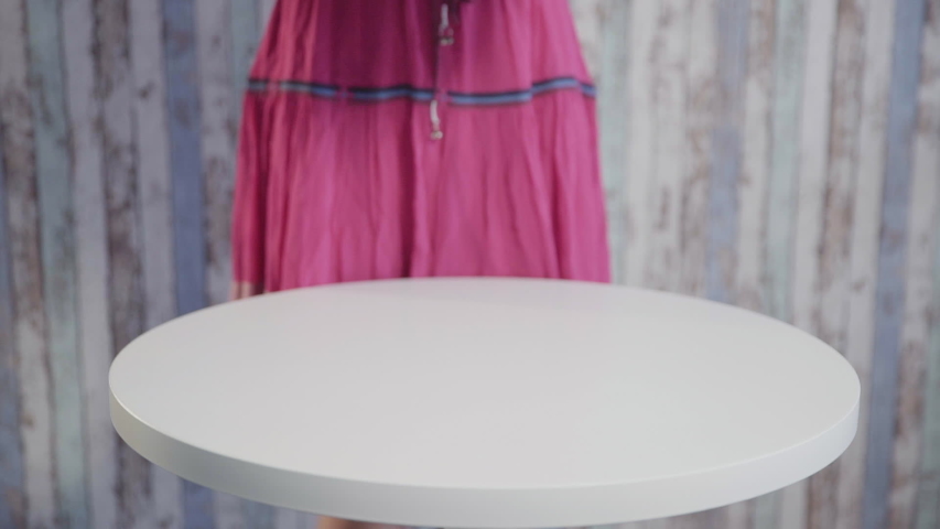 A girl in a dress put a gift box on the table