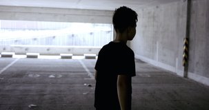 Teenager kid boy soccer player using a chalk to draw goals and targets on a wall in empty abandoned covered parking. 4K UHD 60 FPS RAW graded footage