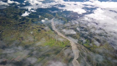 Flying over rugged Papua New Guinea mountains and river above clouds