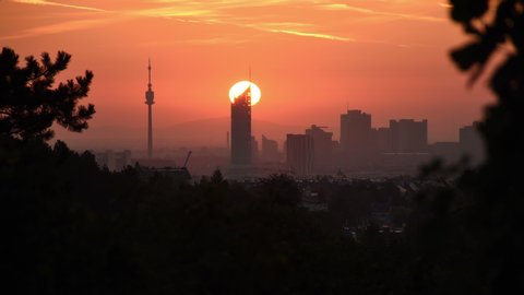 Sunrise time-lapse at Donaucity in Vienna seen from the outskirts. Sunshine dives famous skyscrapers in dazzling bright light, showing merely the silhouettes of the skyline.