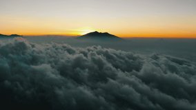 Cinematic aerial view video clip of a beautiful sunset behind Arjuna mountain with amazing wave of clouds