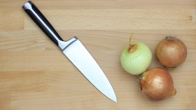 Speeded up clip of onions being chopped on a wooden chopping board.