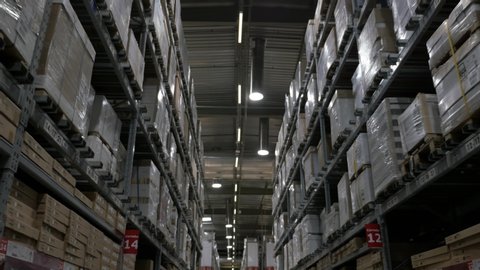 Slow Motion Logistics Industry Warehouse Aisle Travel Shot. Walking through a huge warehouse corridor with shelves full of boxes, dolly shot