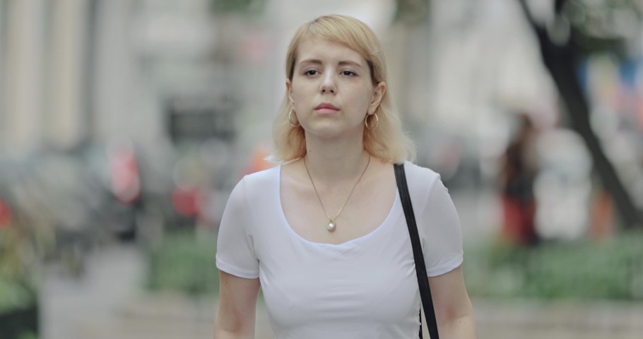 Young blonde business woman walking in the street in a busy cosmopolitan area of the city 4k