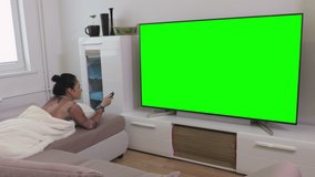 Woman lying on sofa and watching Green Screen Television