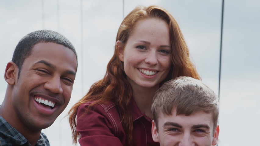 Outdoor Portrait Of Student Friends With Men Giving Women Piggyback Rides