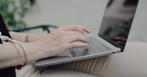 Closeup of young business woman preparing for a meeting on a remote location in a European city. Young woman typing on laptop on a street in Vienna in 4k