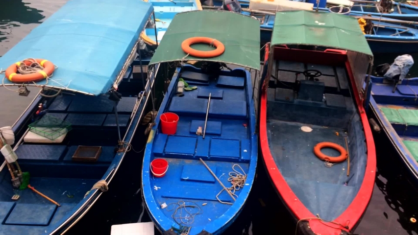 A wide shot of Asian fishermen boats docked, in the village of Hong Kong, name of the village is Sai Kung.