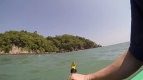 POV shot of a caucasian male paddling a sit-on-top kayak near an desolate island at the sea in Thailand