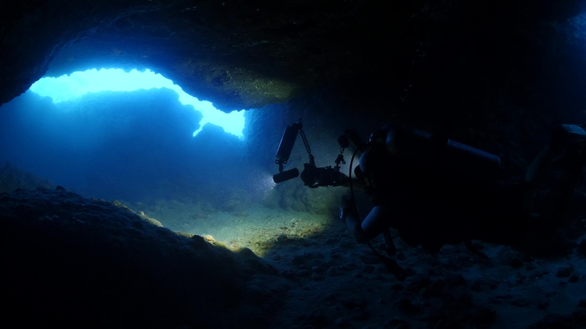 scuba diver photographer filming the cave underwater dark cave  Royalty-Free Stock Footage #1035022793