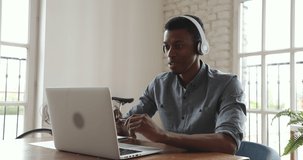 Young african american business man wear wireless headphone video calling teleconferencing on laptop computer at work talk by webcam in online chat in office, videoconference software concept
