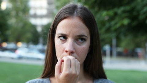 Nervous woman waiting for somebody in the street biting nails
