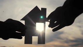 happy family house construction concept. man holding home a paper house in his hands at sunset silhouette lifestyle sunlight. ecology life video symbol