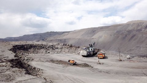 A powerful excavator loads mining trucks. Excavation and loading of rock mass into transport. Timelapse