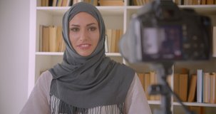 Closeup portrait of young attractive muslim blogger in hijab talking on camera gesturing indoors in apartment