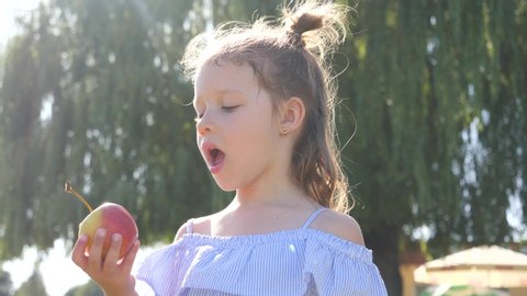 Little kid girl on nature picnic eat bite an apple enjoying delicious fruit