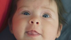 Close up shot in slow motion of baby girl looking at camera with different expressions