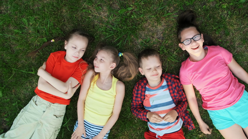 Group of kids lying on grass and having fun in park on a sunny day