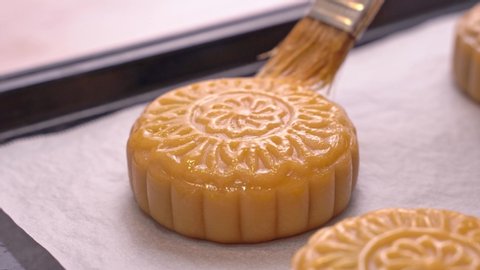 Process of making moon cake for Mid-Autumn Festival - Woman brushing egg liquid on pastry surface before baking. Festive homemade concept, close up. Video de stock