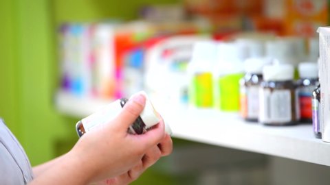 Close Up of pharmacist hands holding and looking medicine bottles In Pharmacy Drugstore. Stock Video