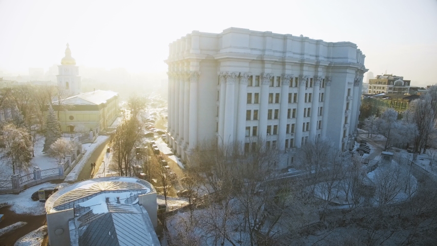 pictorial large public building located on hill top above old town against wide river under clear winter sky upper view. Kyiv downtown, city center, Ukraine, Europe. 4k Aerial Drone Shooting