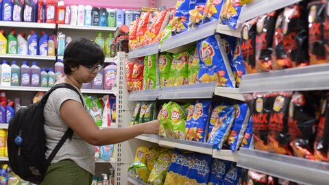 Delhi, India, 2020
Video of a young woman shopping browsing through chips/snacks section on display at the aisle in a modern supermarket departmental store in a mall.
Concept - essential grocery