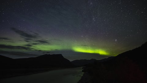 Northern lights and stars above river in the mountains of BC 4K time lapse