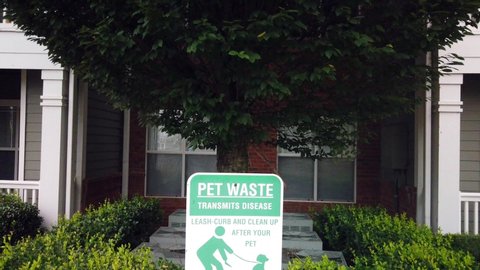 Pet waste sanitation regulations and community rules sign. Panning down slow motion 4k shot of an apartment pet waste notice with fees and fines posted by management.