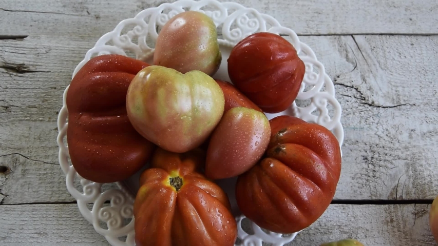 Raw ripe graden tomatoes on wooden background. Vegetarian ingredients, seasonal produce
